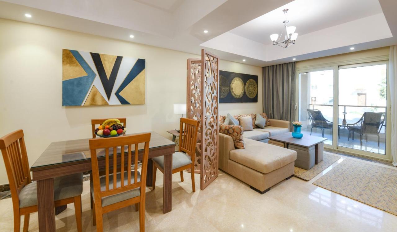 Tolip Resort El Galala Majestic Ain Sukhna Dış mekan fotoğraf The photo shows a modern and stylish interior of a living space. It features a seating area with a plush sofa and decorative cushions, complemented by a wooden coffee table. There is a dining table with wooden chairs nearby. 

On the walls, there are
