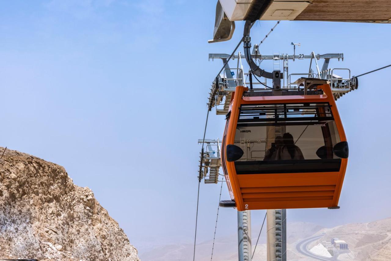 Tolip Resort El Galala Majestic Ain Sukhna Dış mekan fotoğraf The photo shows an orange gondola or cable car hanging on a cable system. The gondola appears to be suspended in the air above a rocky landscape, with a clear sky in the background. There are supporting cables and structures visible, indicating that 