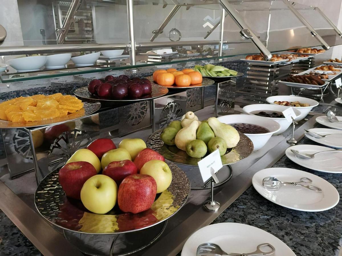 Tolip Resort El Galala Majestic Ain Sukhna Dış mekan fotoğraf The photo displays a buffet setup featuring an assortment of fresh fruits arranged on several tiered trays. There are red and green apples, pears, grapes, and oranges. Adjacent to the fruit display, there are several bowls containing various other fo