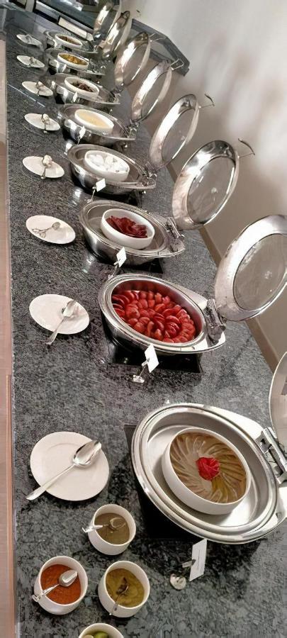 Tolip Resort El Galala Majestic Ain Sukhna Dış mekan fotoğraf The photo shows a buffet setup featuring multiple metal serving trays on a dark granite countertop. One tray contains circular slices of food, possibly sausages or a similar dish, while another bowl holds what appears to be red food items, though it'