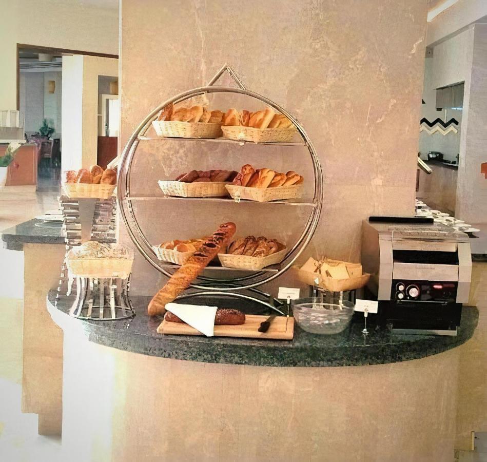 Tolip Resort El Galala Majestic Ain Sukhna Dış mekan fotoğraf The photo shows a display of various types of bread and pastries arranged on a countertop. There are several baskets stacked on a circular stand, filled with different baked goods like croissants and rolls. A long baguette is placed horizontally on a