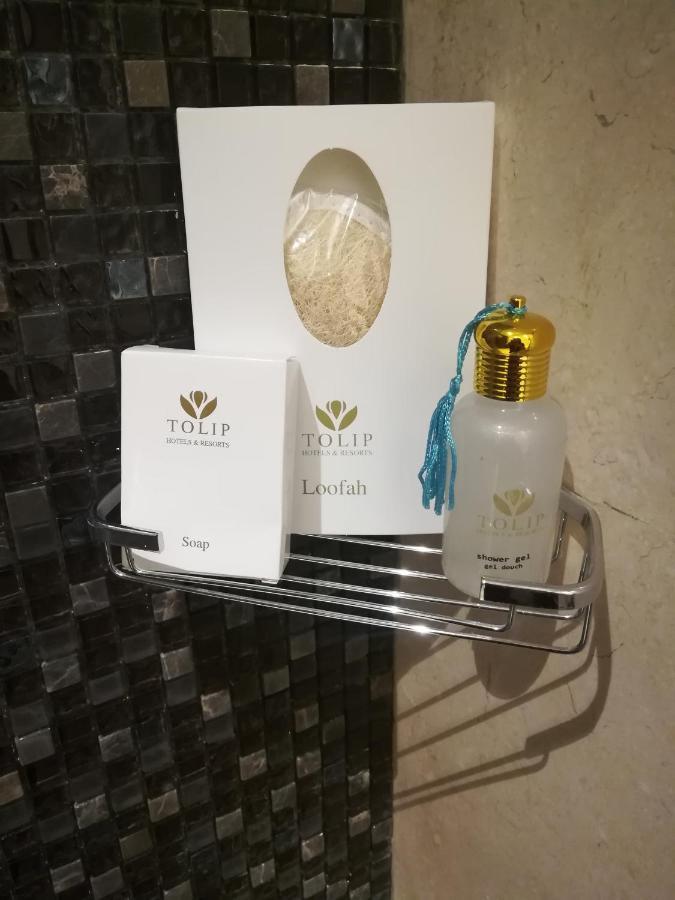 Tolip Resort El Galala Majestic Ain Sukhna Dış mekan fotoğraf The photo shows a small metal shelf containing three items related to personal care. 

1. **Soap**: A white box labeled "TOLIP" with the word "Soap" visible on the front.
2. **Loofah**: A package with the same "TOLIP" branding, containing loofah.
3. 