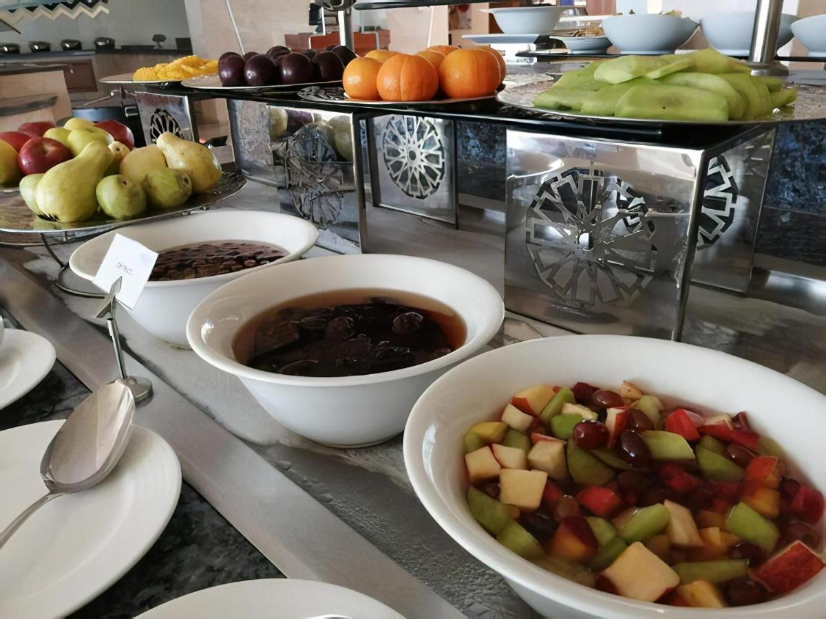 Tolip Resort El Galala Majestic Ain Sukhna Dış mekan fotoğraf The photo shows a buffet-style arrangement of various fruits and fruit dishes. In the foreground, there are several bowls containing different types of fruit. One bowl has a fruit salad made with diced apples, green apples, and possibly other fruits.